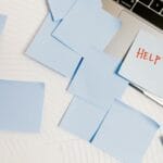 Zabałaganione biurko z laptopem obklejonym kolorowymi karteczkami