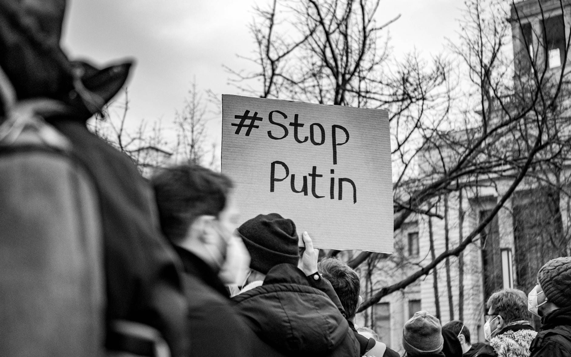 Czarno-białe zdjęcie protestu w Berlinie z transparentem Stop Putin