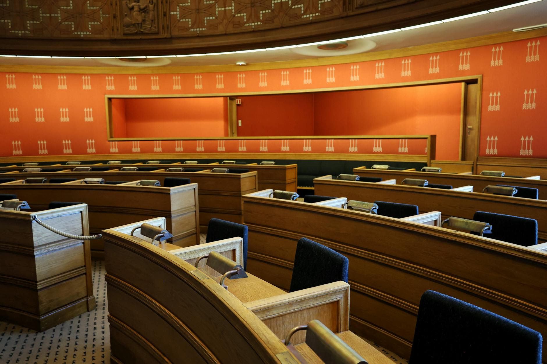 Pustawa sala obrad parlamentu z drewnianymi ławami w Oslo