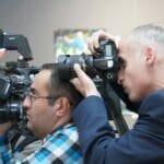 Fotoreporterzy relacjonują wydarzenie w pomieszczeniu, profesjonalny sprzęt