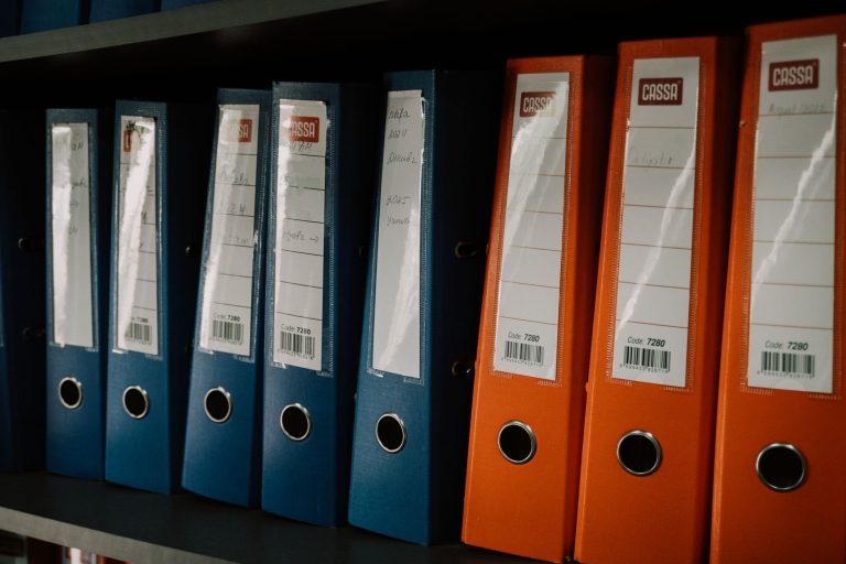 Kolorowe segregatory biurowe ustawione w rzędzie na półce